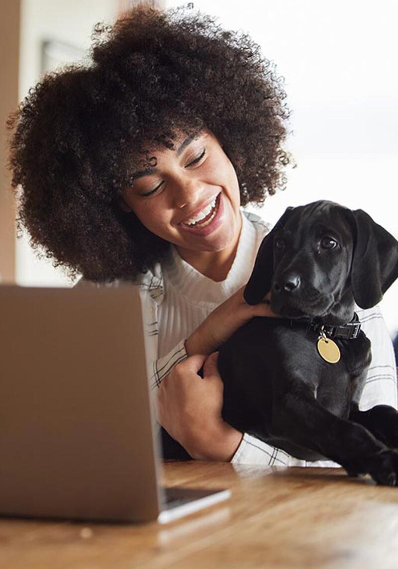 Happy Woman Holding Puppy With Open Laptop